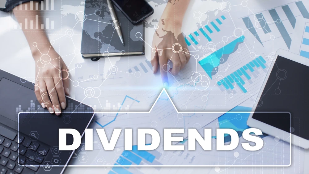 Woman is working with documents, tablet pc and notebook and selecting dividends.